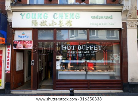London, England - Sept 09, 2015: People at the buffet counter in the window of a Chinese restaurant situated next door to a massage parlour in Chinatown, London, England.