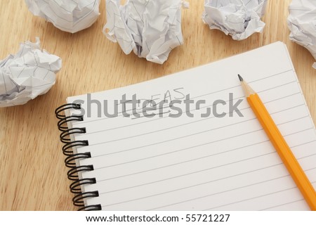 Ideas written on a blank notepad and surrounded by waste paper