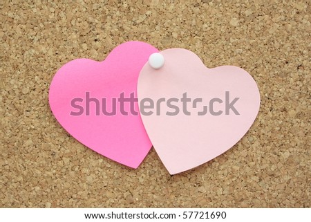 Two heart shaped post it notes pinned to a cork board