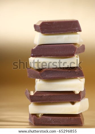 Stack of milk and white chocolate pieces on a coloured paper background with copy space