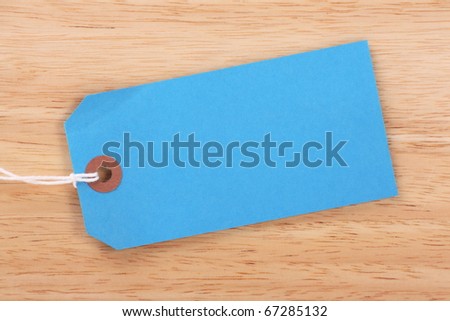 Blank blue paper luggage tag or label on a wood background