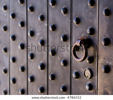 An old studded door opens by pulling a rusty ring.