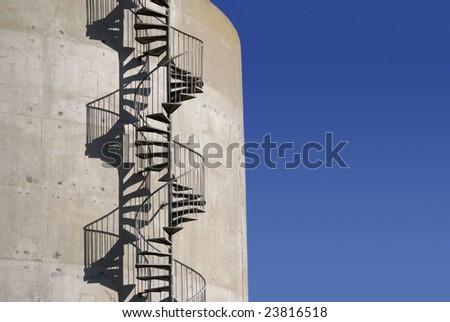 A spiral staircase on the outside of a concrete tank casts interesting shadows.
