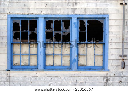 An abandoned building vandalized by rocks thrown at windows.