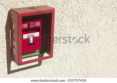 Red fire alarm box with white pull handle.
