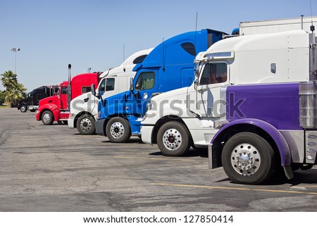 Multiple trucks park in a large parking lot.