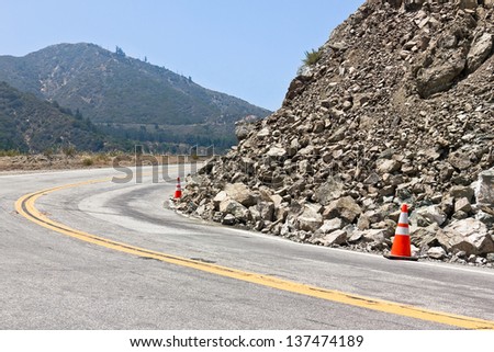 Two safety cones are used for the rock slide on the road.