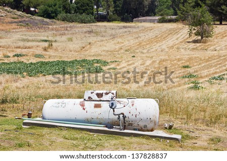 Propane tank sits on a dry out hillside.