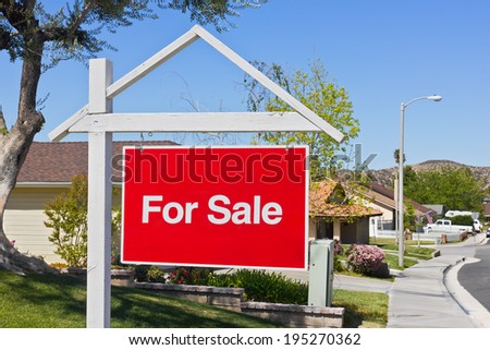 A big red sale sign hangs in the front yard of a house in a suburban community.