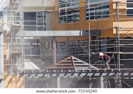 Worker uses compress air to remove dirt from the building.