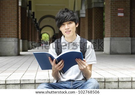 Asian college student sitting student reading on campus