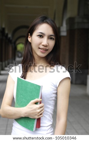 A portrait of young student holding book at campus