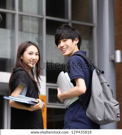 Couple college student sitting holding laptop on campus