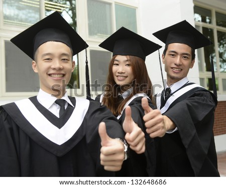 Three standing out from a graduation group smiling on campus