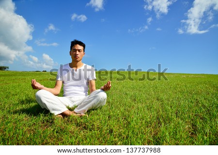 Young man sitting in lotus position out side