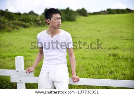 Young man in white cloth posing Grass plain in the Kenting national park, Taiwan