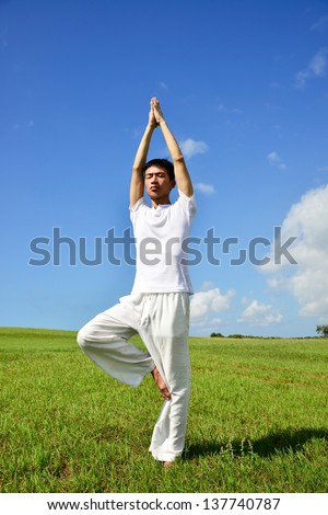 Full body healthy young man doing yoga against sky