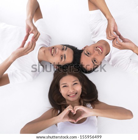 friends posing laying down making the shape of a heart with hands on the floor looking at camera