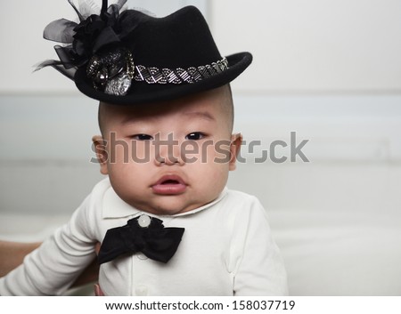 little baby with hat laying in the sofa. looking at the camera