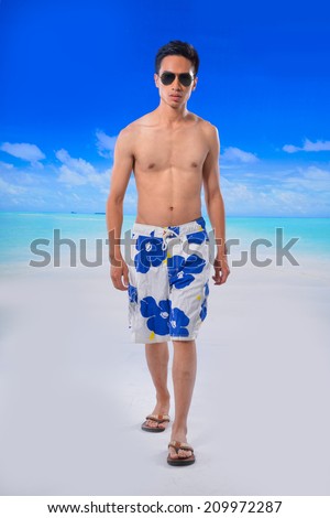 Full body sunny man wearing beach short and Flip Flops walking at beach background