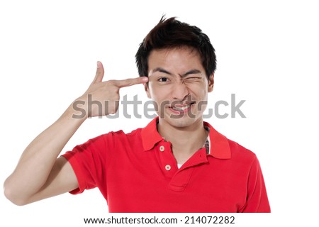 Portrait of a funny young man pointing finger gun gesture to head