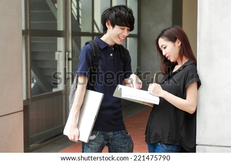 Asian college couple student standing holding book on campus