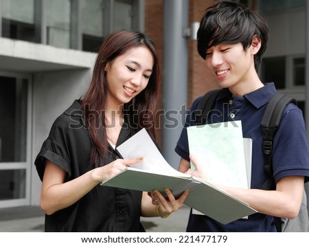 Asian college couple student standing holding book on campus