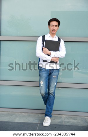 Full body male college student holding laptop at campus
