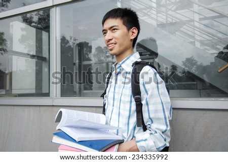 portrait of male college student holding book at campus