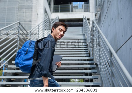 male college student holding laptop at campus