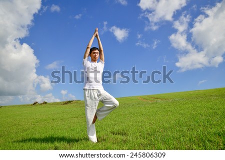Full body healthy young man doing yoga against sky
