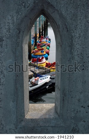 Small water craft viewed through a portal in a cement bridge.