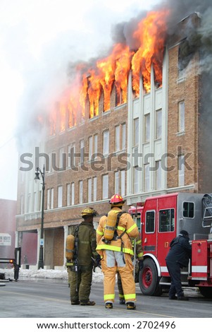 Two Firemen watching an apartment on fire