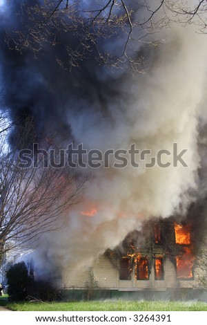 House on fire with smoke billowing from it