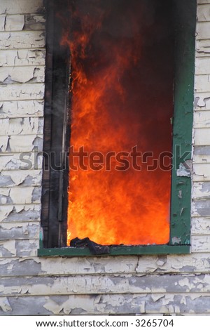 Flames engulfing the inside of a house as seen through a window