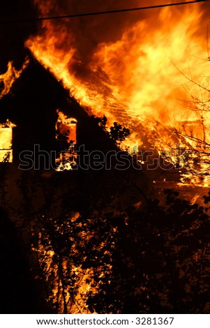 A close-up of a house fire and the shell of the house burning