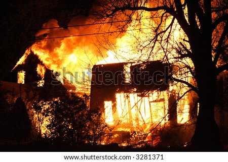 the shell of tow houses burning uncontrollable in the night