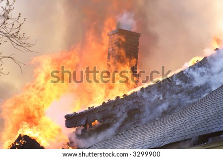 The roof and chimney of a house on fire