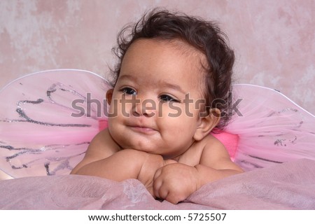 A close-up portrait of a baby with pink fairy wings