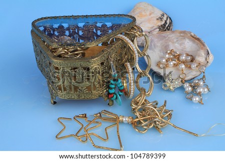 Water on and dripping from vintage gold jewelry box with diamond, rhinestone, pearls, turquoise, mother-of-pearl, earrings, necklaces, pendant and various personal apparel. Sunken treasure simulation.