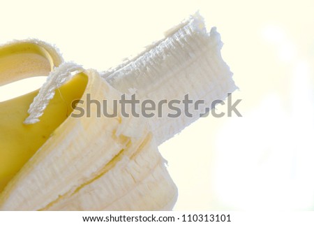 Closeup of partially eaten banana with strong back light and white background.