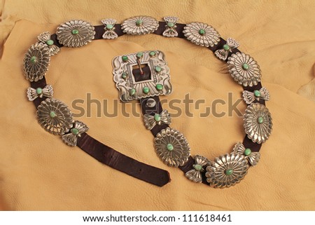 Turquoise gems set in silver conchos of luxurious Native American belt and displayed on soft pliable buckskin leather pieces.