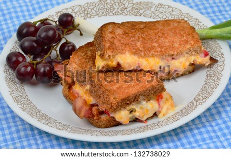 Pimento Cheese Spread on toast with fried bacon and served with scallion and grapes.