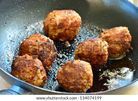 Six meatballs in frying pan being prepared for sandwiches.  Strong back light.