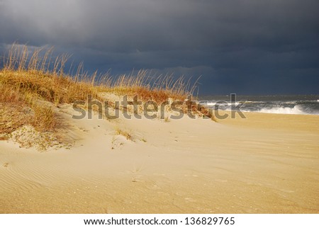 Storm gathering over Atlantic Shores of North Carolina Outer Banks with light on foreground and very dark clouds in background.