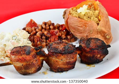 Upscale soul food dinner with skewered pork tenderloin wrapped in bacon and grilled to perfection with baked sweet potato and black eyed peas and macaroni salad.  Peas are a Hoppen John mixture