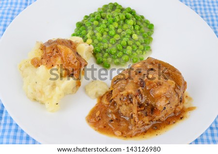 Salisbury Steak or Hamburger Steak in creamy onion gravy with mashed potatoes and english peas in cream sauce; a country cooking favorite.  White plate and blue gingham add country emphasis.