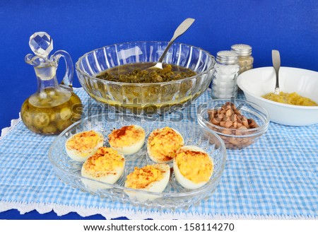 Serving dish filled with deviled eggs on blue gingham place mat with various soul food dishes.