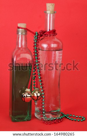 Vintage bottles of Holiday Spirits (alcohol) against red background decorated with golden bells and colorful beads;  a party atmosphere.