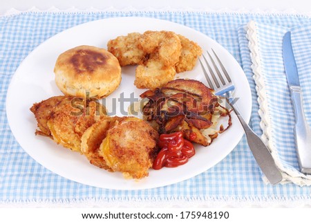A Southern Cooking Favorite -- fried green tomatoes on white plate with deep-fried chicken medallions and sliced potato and onion homefries and a baked biscuit.